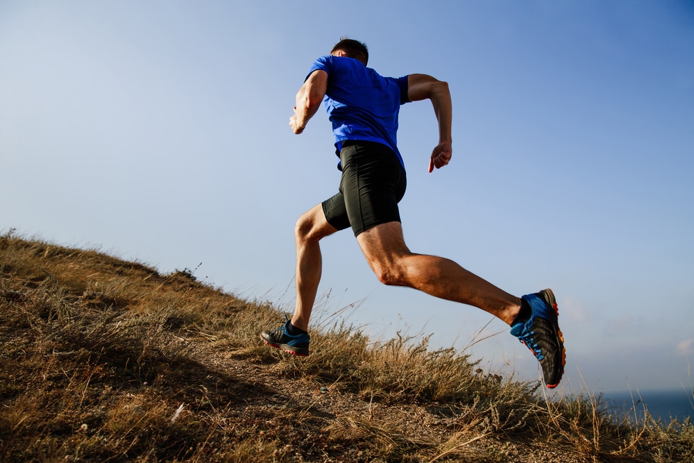Runner ascends a hill, showing prominent varicose veins