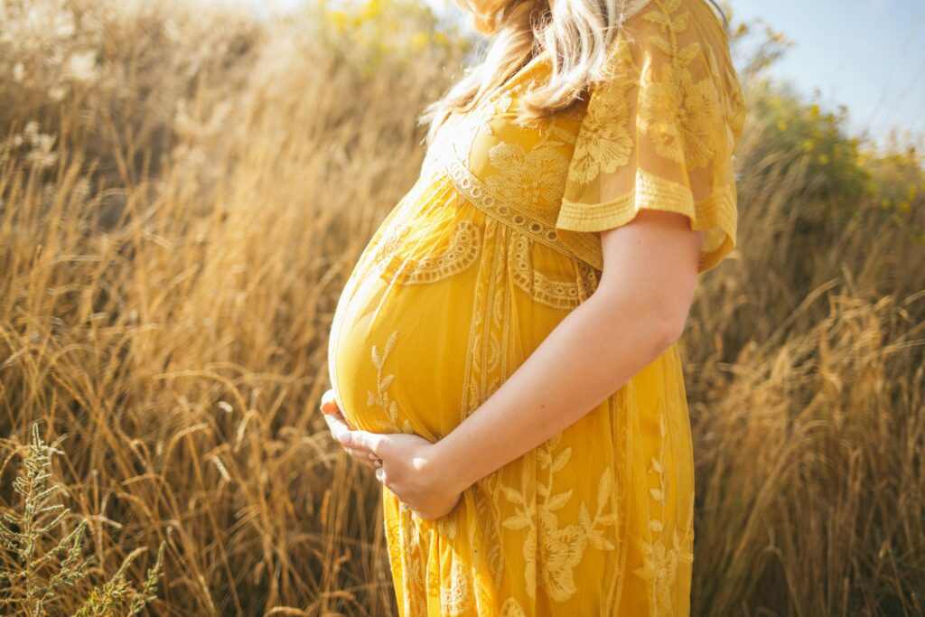 Pregnant woman in a yellow dress in a field